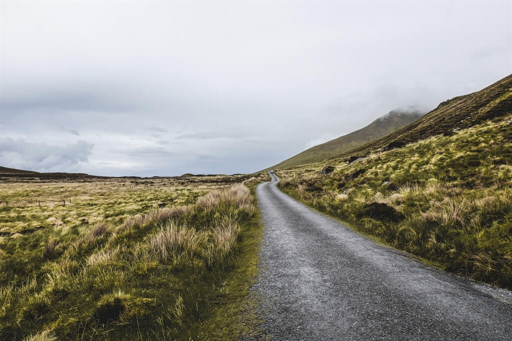 IN GAELICO AN CHONAIR, IN INGLESE CONNOR PASS E IN ITALIANO PASSO CONOR. LA MIA GUIDA TASCABILE MI INFORMA CHE SI TRATTA DI UNO DEI PASSI MONTANI PIÙ ALTI DELL’ISOLA D’IRLANDA. ALTITUDINE: 456M SOPRA AL LIVELLO DEL MARE. UNA DIMENSIONE BEN RIDOTTA SE LA COMPARIAMO A QUELLE DELLE NOSTRE CATENE MONTUOSE. CIONONOSTANTE IL PERCORSO VERSO LA VETTA NON È DEI PIÙ SEMPLICI, LA STRADA È LARGA QUANTO UNA PICCOLA VETTURA, COSTEGGIATA DA UN’IRREGOLARE MURETTO IN PIETRA E IN CASO DI PRECIPITAZIONI PUÒ ESSERE DAVVERO PER